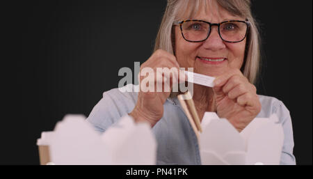 Portrait of joyful senior woman reading fortune on solid gray background Stock Photo