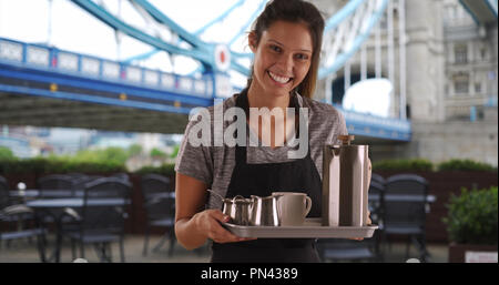 Pretty waitress carrying tray with coffee in England Stock Photo