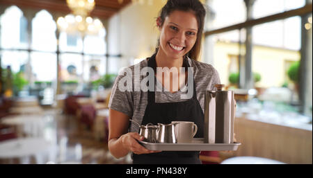 Pretty waitress in restaurant carrying tray with coffee beverages Stock Photo