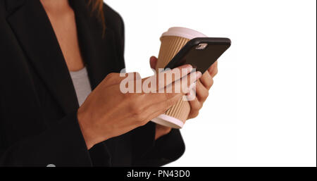 Close up of business womans hands holding cell phone and coffee while texting Stock Photo