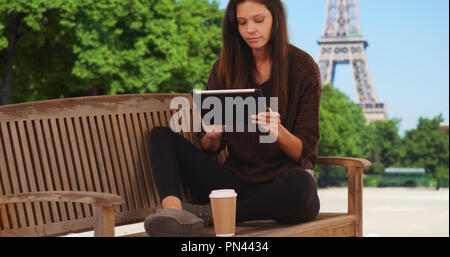 Female tourist in Paris planning vacation on tablet near Eiffel Tower Stock Photo