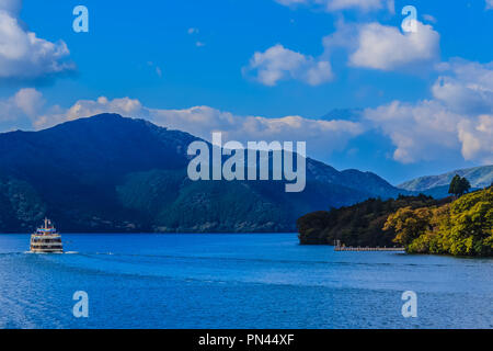 Tourist cruise ship on lake Ashi with mountains and blue sky on the background Stock Photo
