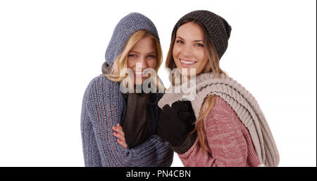 Portrait of 2 Caucasian women in winter clothes staying warm on white copy space Stock Photo