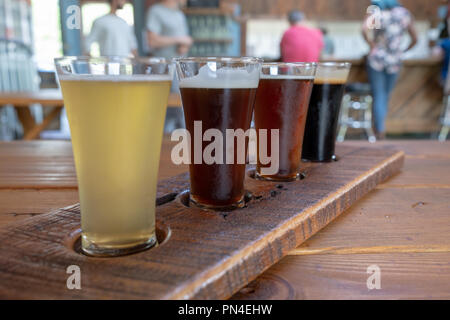 Flight of four beers served in tall glasses on a wooden tray Stock Photo