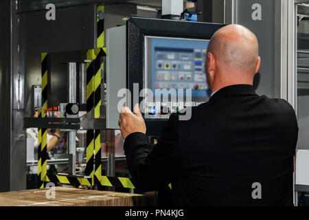 factory engineer controlling and pressing important technology button at control panel of an automatic machine in the manufacturing. Stock Photo