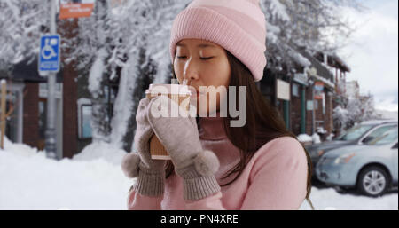 Close up of Asian millennial holding cup in snowy old town Stock Photo