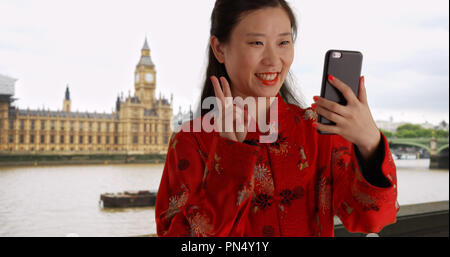 Happy millennial woman taking selfie with smartphone in London UK Stock Photo