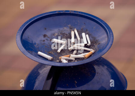 Cigarette butts in ashtray on city street close-up Stock Photo