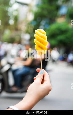 Woman holding pineapple slice on a wooden stick Stock Photo