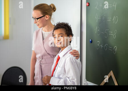 boy solving addition and subtraction on board. schoolboy writing solution of mathematical operation Stock Photo
