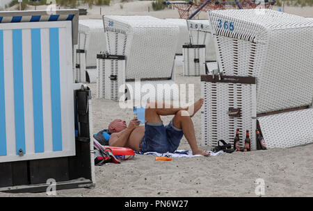 20 September 2018, Mecklenburg-Western Pomerania, Warnemünde: Visitors to the beach use the beach chairs as wind protection. In the coming days clouds, wind and colder temperatures are expected. Photo: Bernd Wüstneck/dpa-Zentralbild/dpa Stock Photo