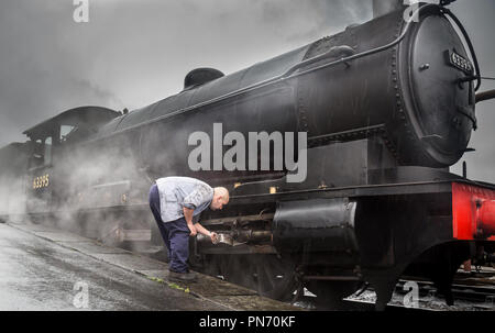 Kidderminster, UK. 20th September, 2018. UK weather: staff at Severn Valley Railway soldier on even though the rain continues. Persistent rain doesn't dampen the spirits of staff or travellers as vintage UK steam locomotive 63395 receives an oil service from crew at the Kidderminster station. It is full steam ahead when steam train crew have finished with the oil can, for the beginning of this heritage railway's Autumn Steam Gala. Credit: Lee Hudson/Alamy Live News Stock Photo