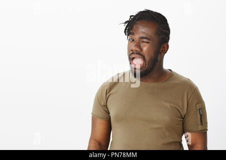 If you know what I mean. Portrait of intriguing funny african-american in casual t-shirt, winking with opened mouth, making hints and being in joyful mood, agreeing with friend to make something Stock Photo
