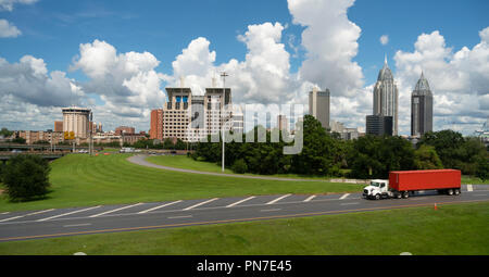 A trucking shipping container matches the sky behind the downtown Mobile Alabama city skyline. Stock Photo