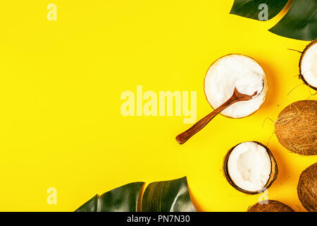 Coconut oil and coconuts on a background with tropical leaves. Stock Photo