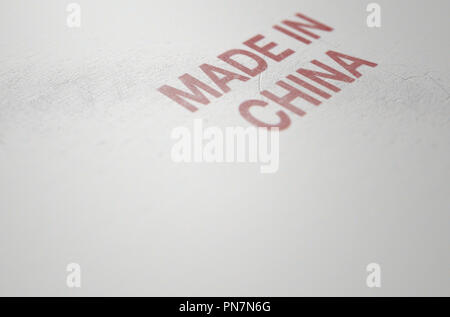 An extreme close up of a worn print sign that reads made in china on a flat white plastic product surface - 3D render Stock Photo