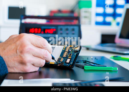 technician repairing broken mobile phone Stock Photo