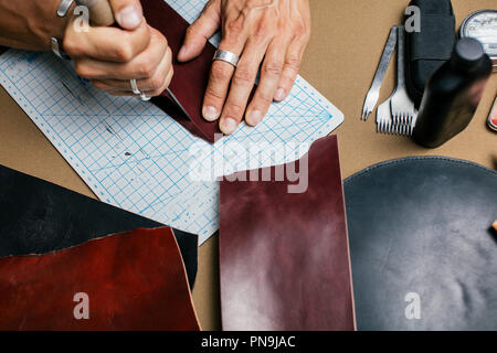 Close up of skinner craftsman working with natural leather using craft tools. Stock Photo