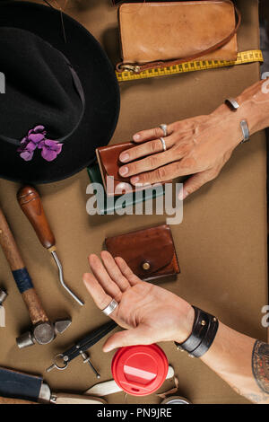 Leather goods master and handmade leather wallets. Workflow in the workshop. Stock Photo