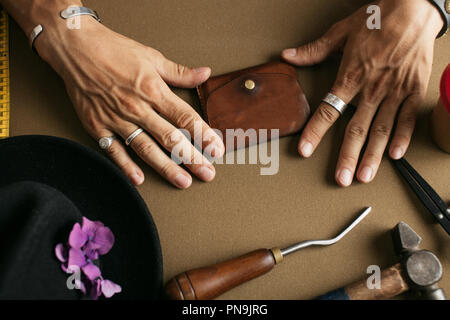Leather goods master and handmade leather wallets. Workflow in the workshop. Stock Photo