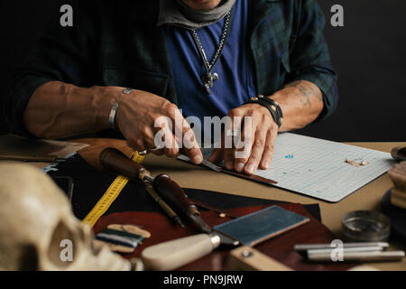 Leather goods master and handmade leather wallets. Workflow in the workshop. Stock Photo