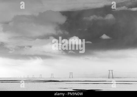 Marching sculptural row of electric power pylons carrying electricity cables across the landscape in South East Iceland Stock Photo