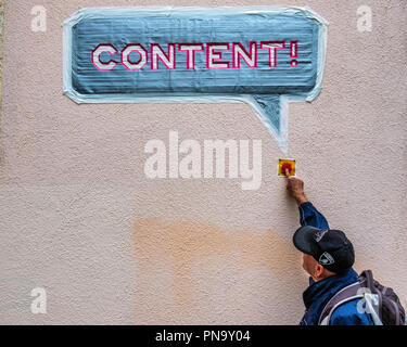 Berlin, Prenzlauerberg. Urban political art. Content! sign with small red press for peace button on a city wall. Senior elderly man presses button Stock Photo