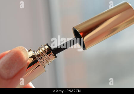 woman hand with finger holds professionall tool black lash mascara brush closeup Stock Photo