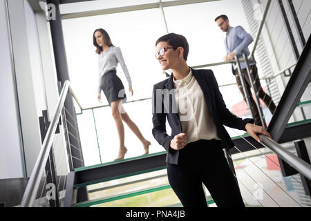Confident business partners walking down in office building and talking Stock Photo
