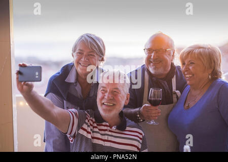 group of people senior adults caucasian having fun celebrating together outdoor at home in the terrace with rooftop view. taking picture selfie with p Stock Photo