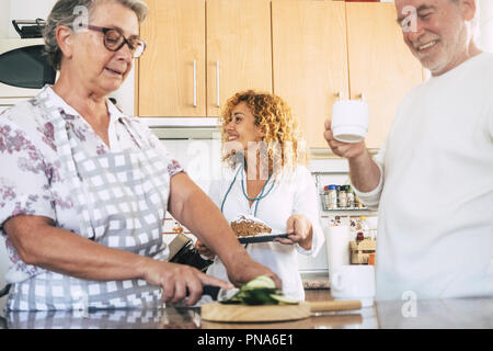 happy family at home preparing dinner or lunch together in the kitchen smilng and having fun. cheerful caucasian people working together in friendship Stock Photo