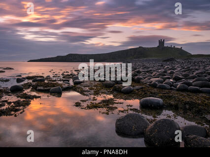 Dunstanburgh Castle at sunrise, Northumberland coast, England, UK Stock Photo