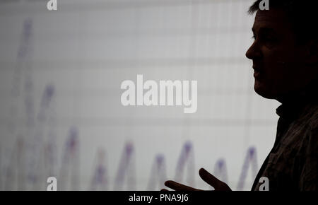A man delivers a presentation in front of a line graph. Stock Photo