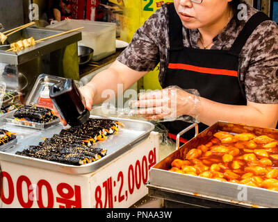 Seoul, South Korea - June 21, 2017: Woman vendor serving customers at Gwangjang Market in Seoul. Stock Photo