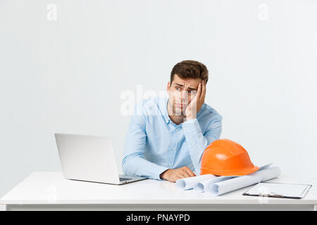 Focused serious hardworking engineer busy working on big architectural project late, sitting at his workspace using digital tablet pc. People, job, occupation and profession concept Stock Photo