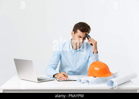 Focused serious hardworking engineer busy working on big architectural project late, sitting at his workspace using digital tablet pc. People, job, occupation and profession concept Stock Photo