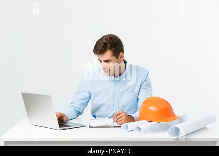 Focused serious hardworking engineer busy working on big architectural project late, sitting at his workspace using digital tablet pc. People, job, occupation and profession concept Stock Photo