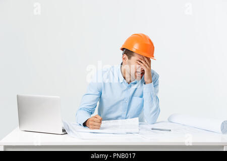 Focused serious hardworking engineer busy working on big architectural project late, sitting at his workspace using digital tablet pc. People, job, occupation and profession concept Stock Photo