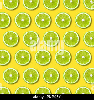 Green lime slices pattern on vibrant yellow color background. Minimal flat lay food texture Stock Photo