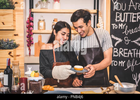 Young couples making bakery donuts and bread at bakery shop as business ownership entrepreneur. Husband and wife cooking together in kitchen. Happines Stock Photo