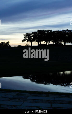 Stockholm, Sweden - September 13 2018: The meditaion grove Almhöjden reflected in a pond, at the Woodland Cemetery (world heritage) at twilight. Symme Stock Photo