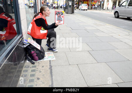 Woman selling the Big Issue (magazine the help the homeless have an income) in the street, London, England, UK Stock Photo