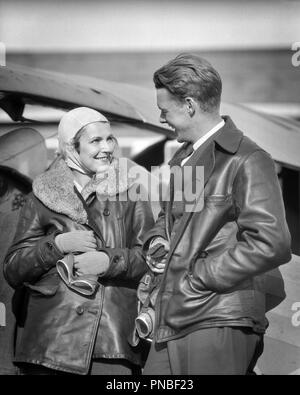 1930s COUPLE WEARING LEATHER JACKETS HOLDING GOGGLES LOOKING AT TALKING TO EACHOTHER STANDING BY AIRPLANE  - a4378 HAR001 HARS 1 AIRCRAFT FACIAL STYLE TEAMWORK PLEASED JOY LIFESTYLE PLANES FEMALES MARRIED SPOUSE HUSBANDS HEALTHINESS FRIENDSHIP HALF-LENGTH LADIES PERSONS GOGGLES MALES TRANSPORTATION EXPRESSIONS B&W PILOTS HAPPINESS CHEERFUL ADVENTURE AIRPLANES STYLES EXCITEMENT AT BY TO AVIATION OCCUPATIONS SMILES AVIATOR ESCAPE JOYFUL STYLISH AVIATRIX FASHIONS TOGETHERNESS WIVES BLACK AND WHITE CAUCASIAN ETHNICITY COPILOT EACH OTHER HAR001 JACKETS OLD FASHIONED Stock Photo