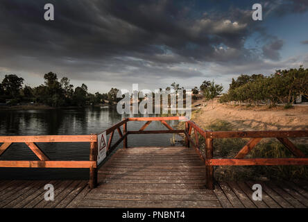 Wooden jetty and gazebo over the lake in Sao Domingos Mine with warning sign and cloudy sky Stock Photo