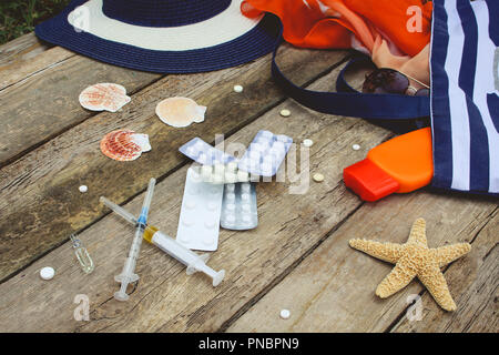 Summer women's beach accessories for your sea holiday and pill on old wooden background. Concept of medication required in journey Stock Photo