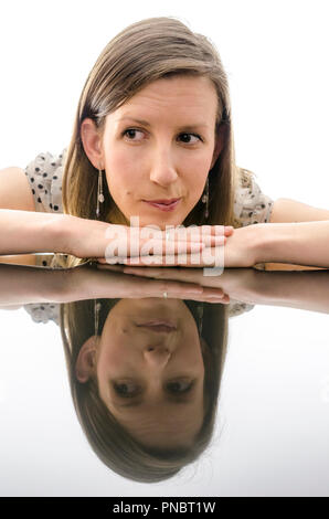 Woman showing emotions of doubts while leaning on a table with reflection. Stock Photo