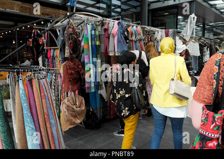 Rear back view of women walking near a scarf stall 'Kashimi Scarves' in Spitalfields Market near Brick Lane in East London E1 UK  KATHY DEWITT Stock Photo