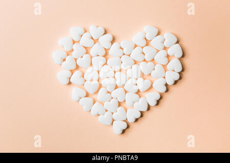 Heart-shaped pills on a beige background. Medical content Stock Photo