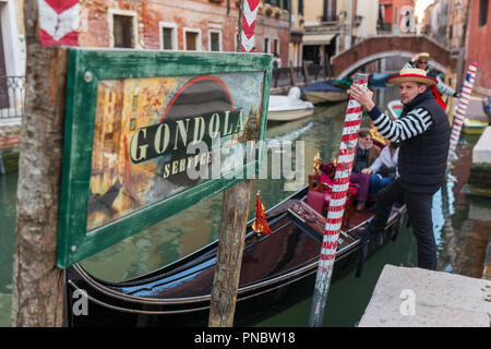 Venice, Italy - March 22, 2018: Gondola parking on a water canal in Venice with the Gondola service sign Stock Photo