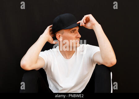 Fashion handsome young man in a black cap with a white shirt on a black background Stock Photo